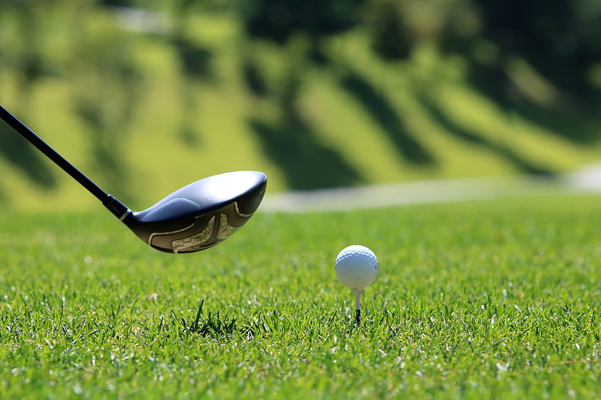 Golf Driver And Ball On Tee In Lush Green Grass