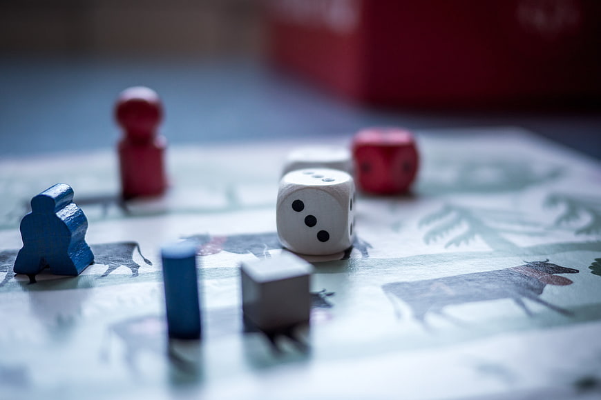 Close-up of board game dice and colorful pawns on a patterned surface