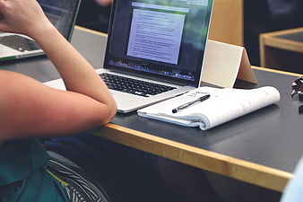 Student studying with laptop and notebook at desk