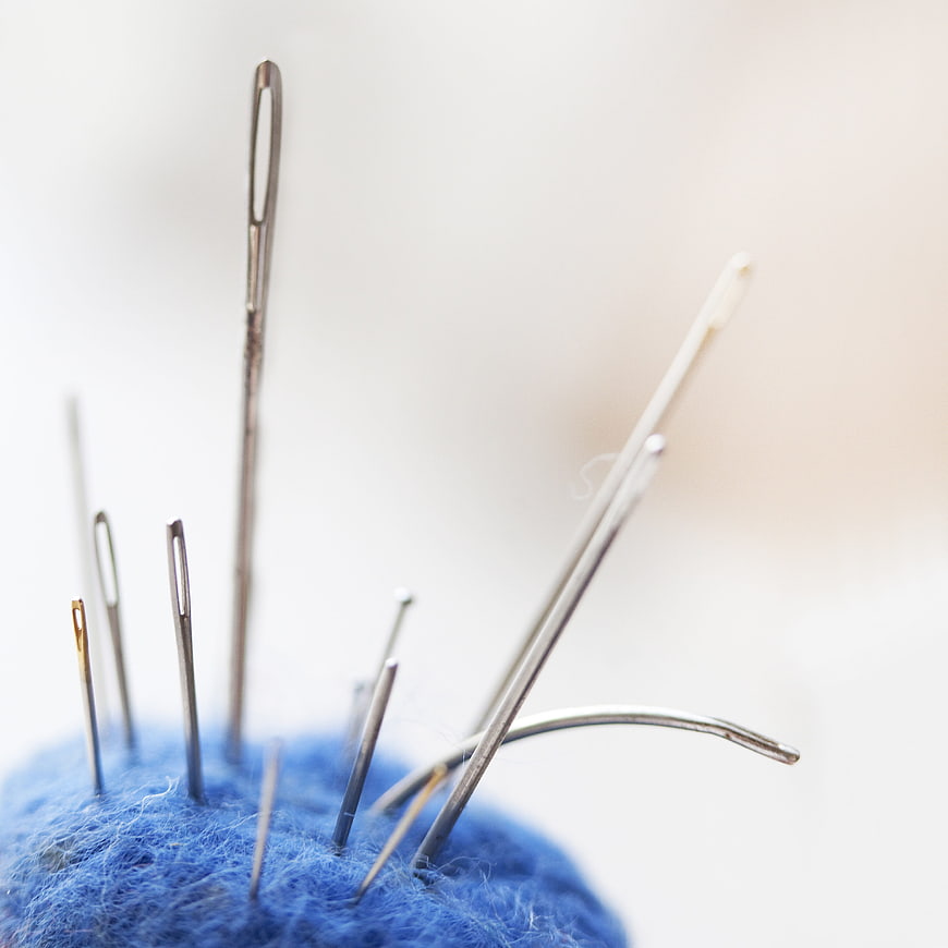 Close-up of sewing needles in blue felt pincushion