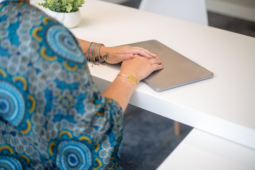 Woman with hands on closed laptop at white desk