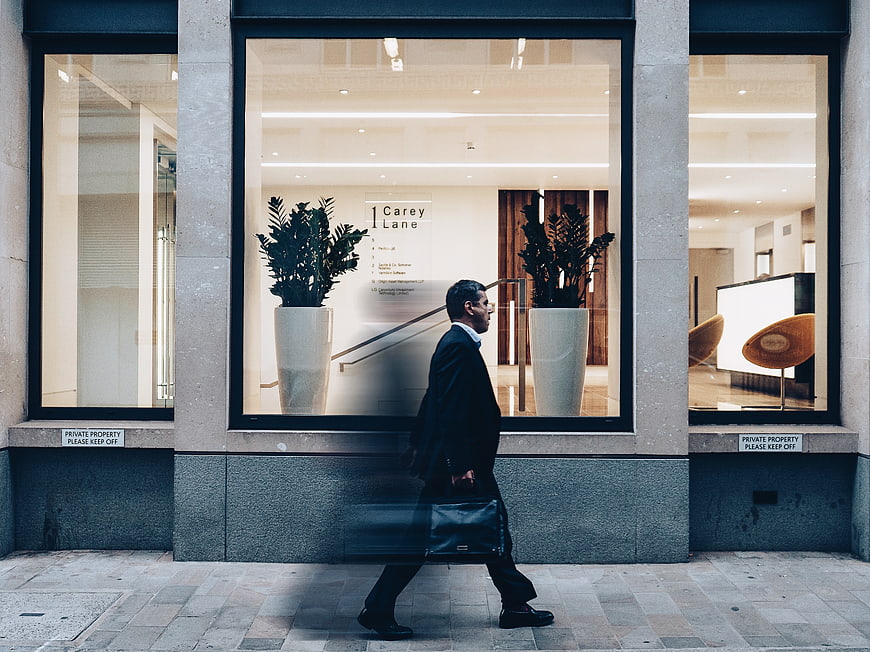 Businessman walking past modern office building window