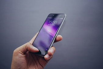 Hand holding smartphone with purple lock screen wallpaper