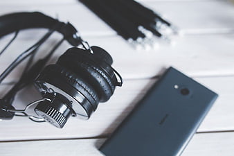 Black Headphones and Smartphone on White Wooden Table