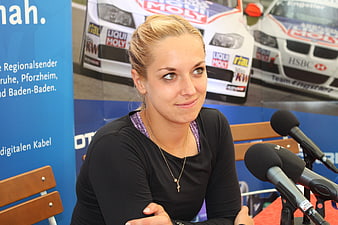 Blonde female athlete seated at press conference with microphones