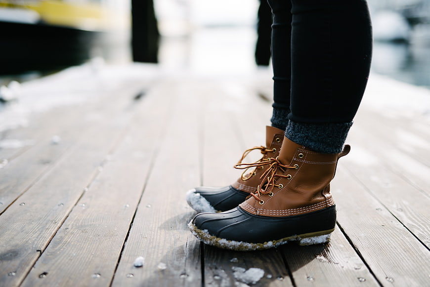 Woman's winter boots on snowy wooden dock