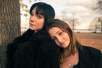 Two Young Women Friends Leaning Against Tree In Autumn Park