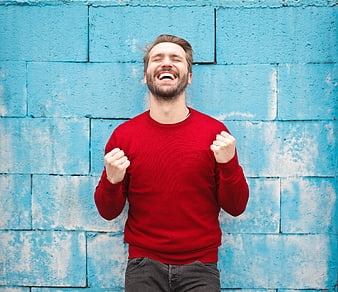 Happy Man Celebrating with Fists Raised Against Blue Wall