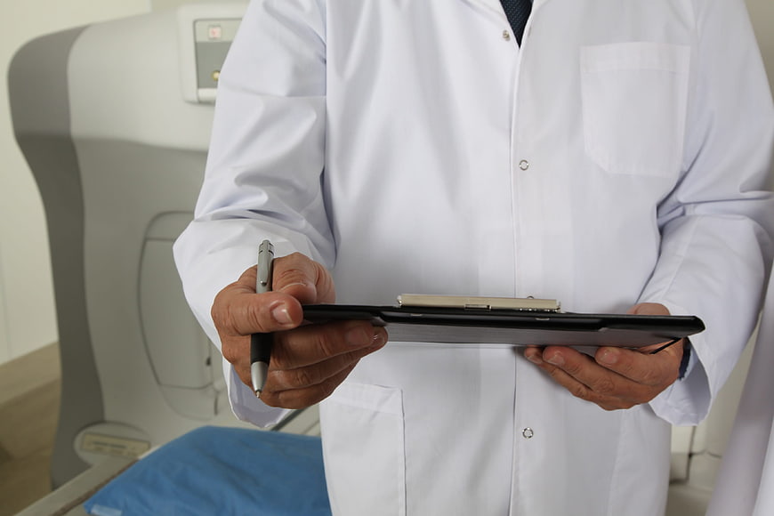 Doctor holding clipboard and pen in hospital room