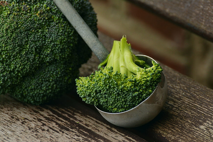 Fresh Broccoli in Metal Scoop on Wooden Table