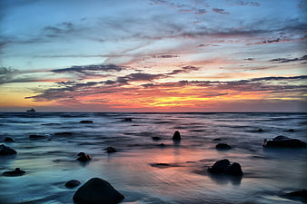 Serene Sunset Seascape with Silhouetted Rocks and Misty Water
