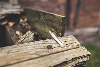 Smoking cigarette resting on weathered wooden planks