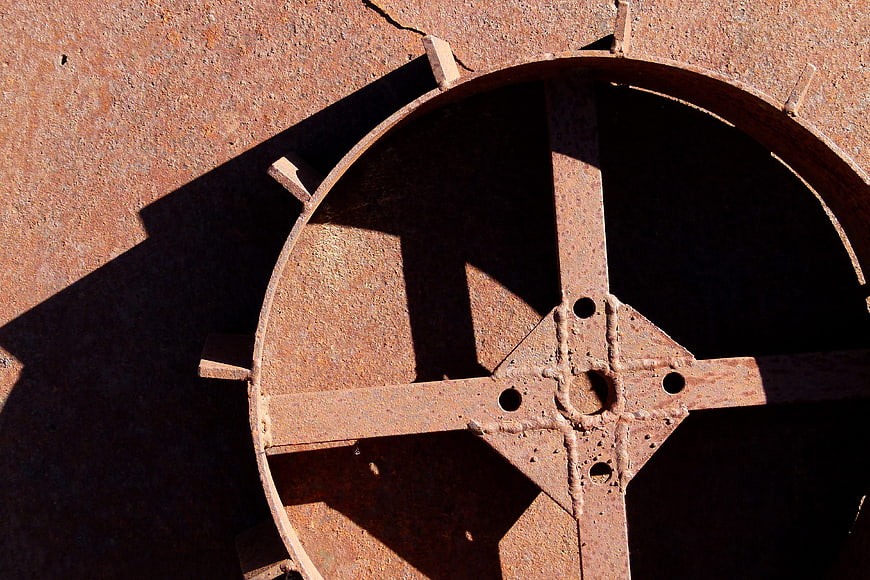 Close-up of rusty iron wheel mechanism with deep shadows