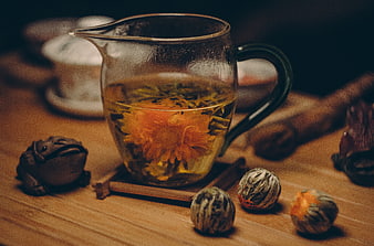Glass teapot with blooming chrysanthemum tea on wooden table