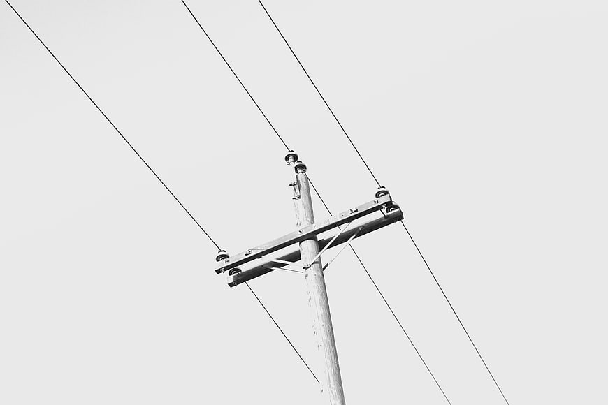 Black and white utility pole with power lines against sky