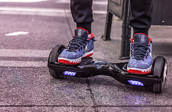 Person Riding Black Hoverboard With Blue LED Lights On City Pavement