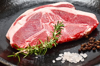 Raw lamb T-bone steak with rosemary, salt, and peppercorns