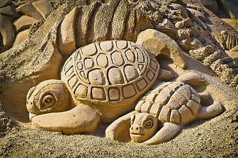 Detailed sand sculpture of mother and baby sea turtles