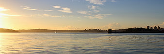 Panoramic Sunset Over Calm Water With City Skyline Silhouette