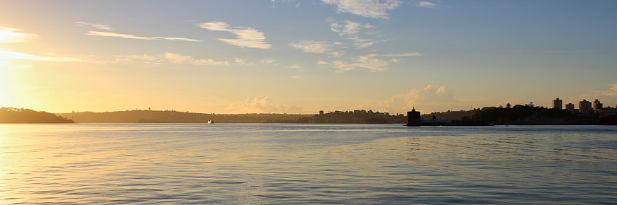Panoramic Sunset Over Calm Water With City Skyline Silhouette