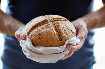 Hands Holding Freshly Baked Artisan Bread Loaf