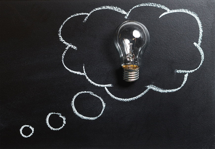 Light bulb inside chalk thought bubble on blackboard
