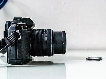 Black DSLR Camera and SD Card on White Glass Desk