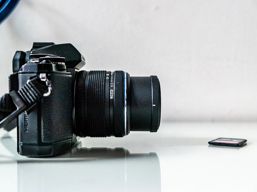 Black DSLR Camera and SD Card on White Glass Desk