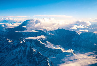 Aerial View of Snow-Capped Mountain Peaks Above Clouds