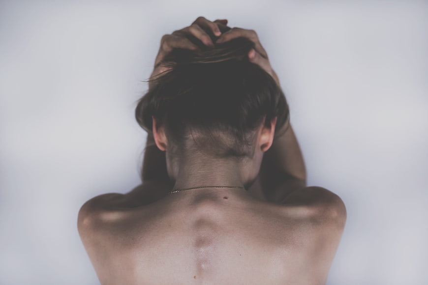 Woman holding head in distress against white background