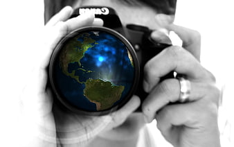 Photographer holding camera with globe reflection in lens