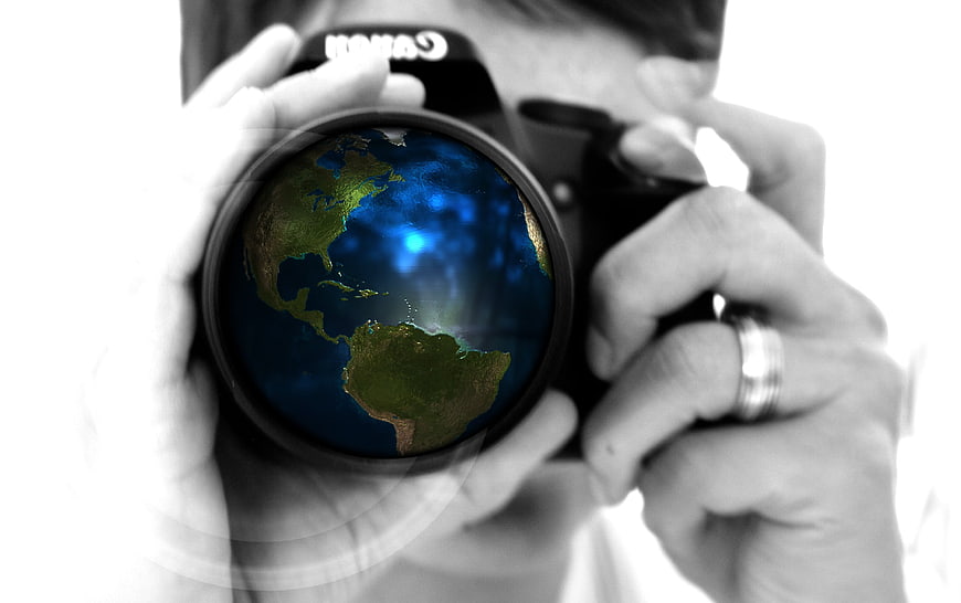 Photographer holding camera with globe reflection in lens