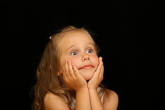 Portrait of a surprised little girl with hands on cheeks