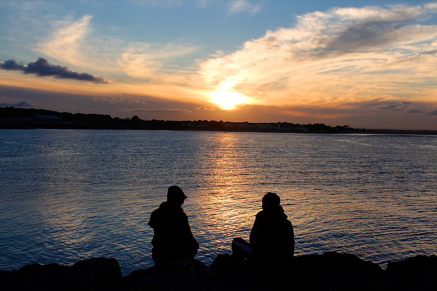 Silhouette of couple watching sunset over water