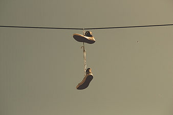 Vintage sneakers hanging on a wire against a muted sky