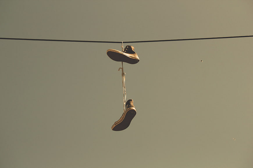 Vintage sneakers hanging on a wire against a muted sky