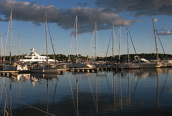 Sailboats docked in a calm marina with reflections