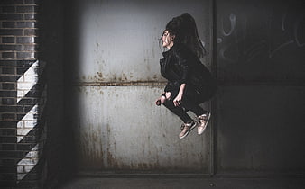 Woman jumping in dark urban alley with graffiti