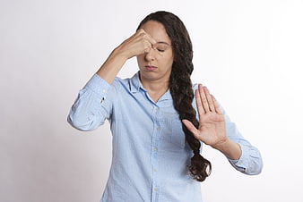 Tired woman rubbing eyes and gesturing stop against white background