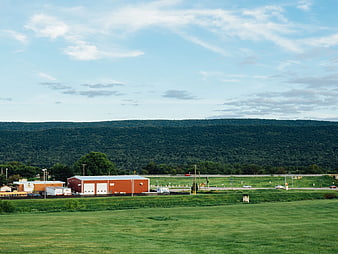 Rural Landscape with Red Barn and Forested Mountain