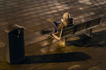 High angle view of person in hoodie on bench at night