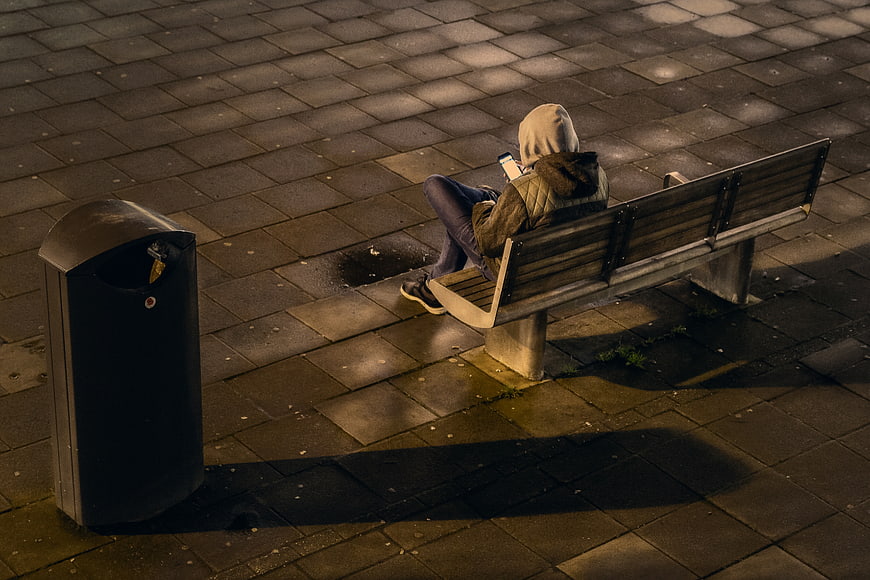 High angle view of person in hoodie on bench at night