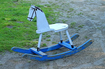 Vintage White and Blue Wooden Rocking Horse on Sandy Ground