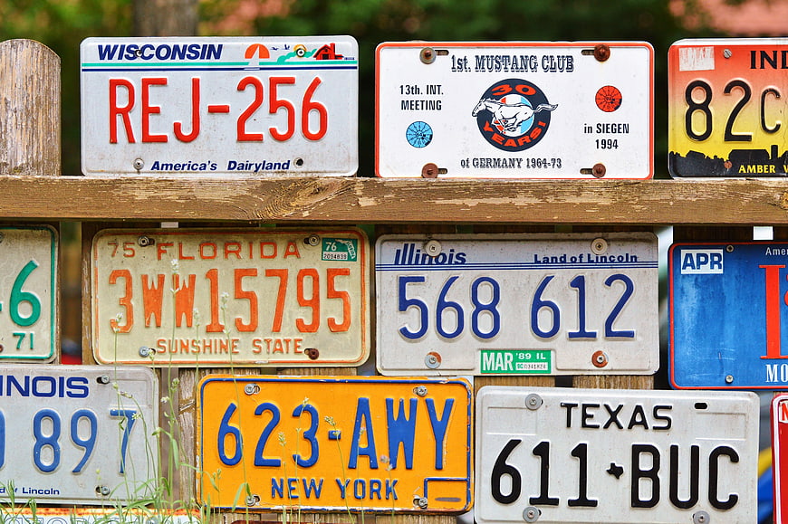 Collection of vintage American license plates mounted on a wooden fence