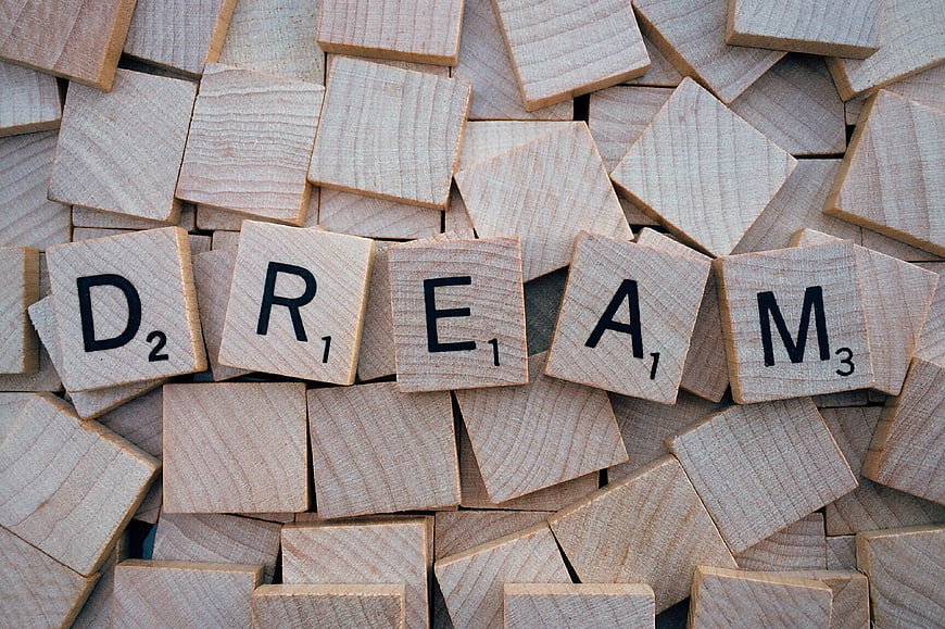 Wooden Scrabble Tiles Spelling Dream on Scattered Background
