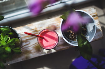 Overhead view of pink smoothie with plants on wooden board