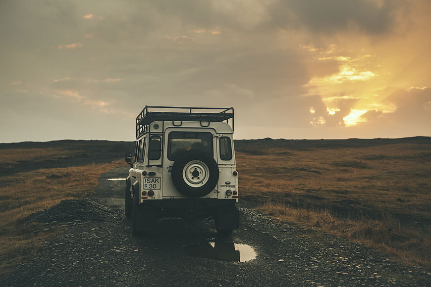 White Land Rover Defender on Gravel Road at Sunset