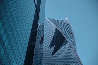 Low angle view of modern glass skyscrapers against blue sky