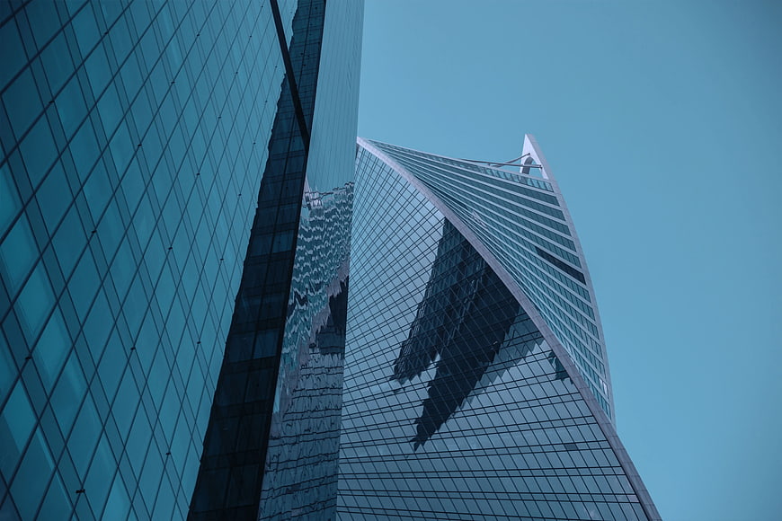 Low angle view of modern glass skyscrapers against blue sky