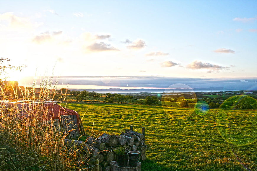 Sunset over rolling green hills and distant ocean landscape